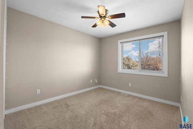 carpeted empty room with visible vents, a ceiling fan, and baseboards