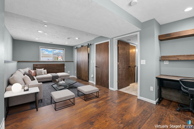 living room with wood finished floors, a textured ceiling, baseboards, and a barn door