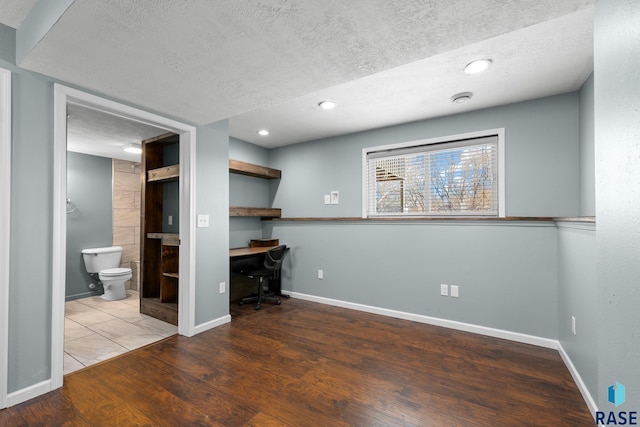 interior space featuring recessed lighting, a textured ceiling, baseboards, and wood finished floors