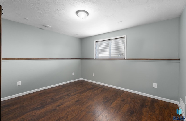 unfurnished room featuring a textured ceiling, baseboards, and wood finished floors