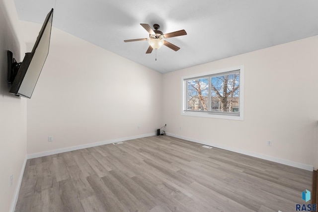 spare room with ceiling fan, vaulted ceiling, light wood-type flooring, and baseboards