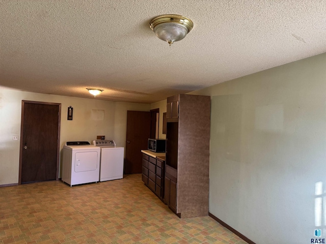 kitchen featuring a textured ceiling, washer and clothes dryer, baseboards, light countertops, and stainless steel microwave