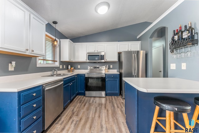 kitchen with white cabinets, appliances with stainless steel finishes, blue cabinets, a kitchen bar, and a sink