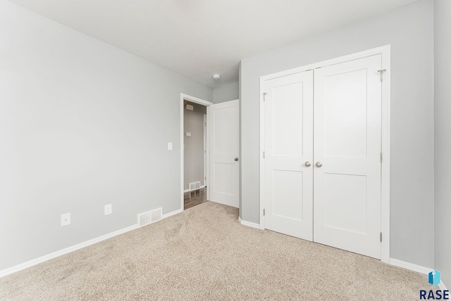 unfurnished bedroom with carpet flooring, baseboards, visible vents, and a closet