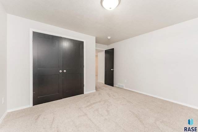 unfurnished bedroom featuring visible vents, baseboards, a textured ceiling, and carpet flooring