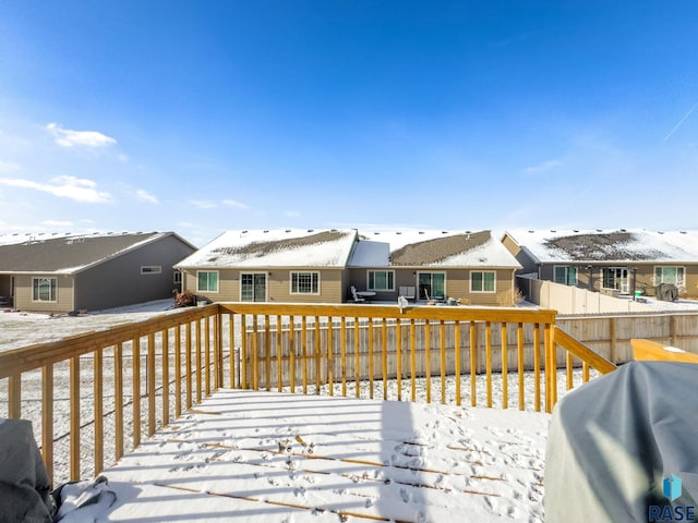 snow covered deck featuring a residential view, area for grilling, and fence