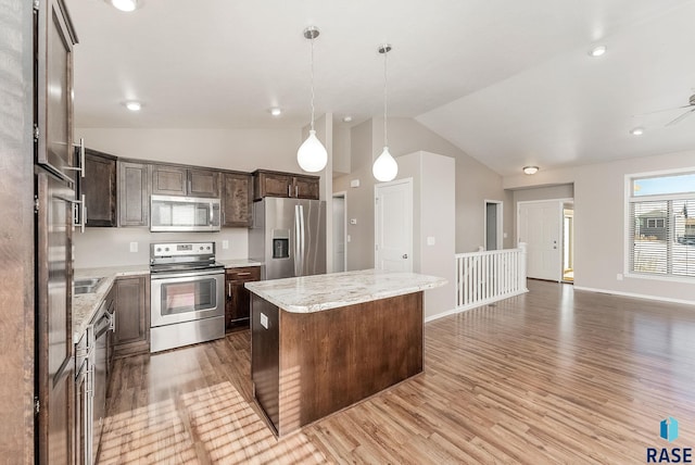 kitchen with pendant lighting, light wood-style flooring, a center island, dark brown cabinetry, and appliances with stainless steel finishes