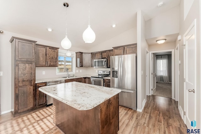 kitchen with a sink, hanging light fixtures, dark brown cabinets, appliances with stainless steel finishes, and a center island