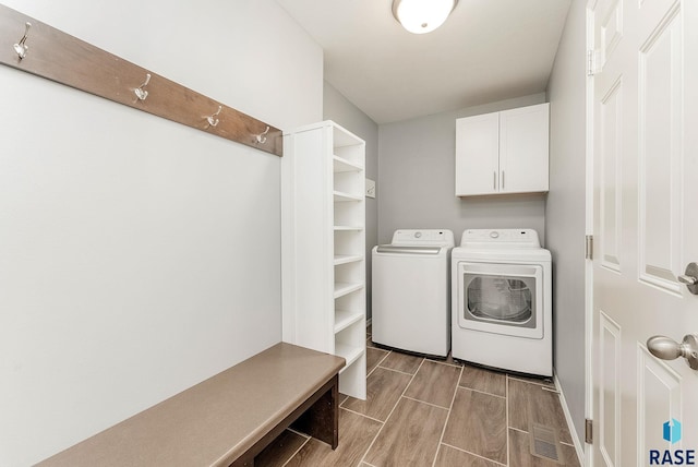 laundry room featuring washing machine and clothes dryer, cabinet space, and wood finish floors