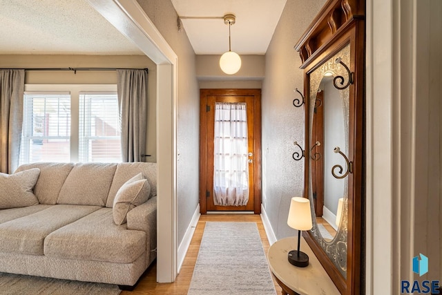 entrance foyer featuring light wood-style flooring, baseboards, and a textured wall