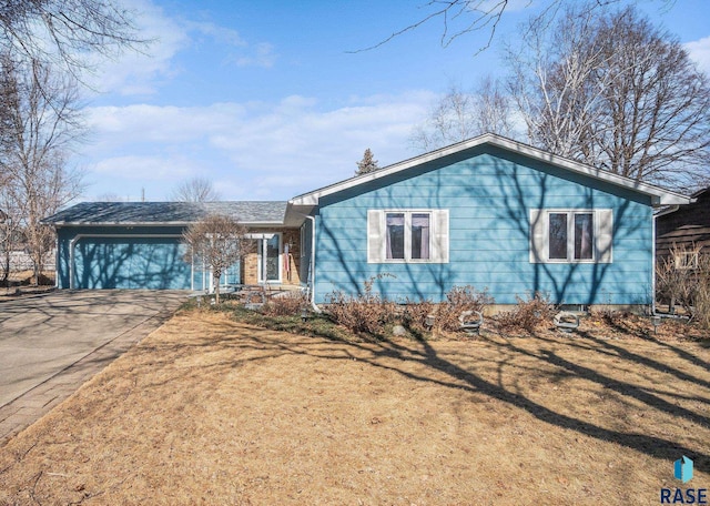 ranch-style home featuring a front yard, driveway, and an attached garage