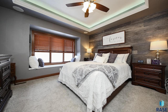 bedroom featuring carpet floors, a tray ceiling, ceiling fan, and baseboards