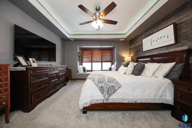 bedroom featuring light carpet, ceiling fan, and a raised ceiling