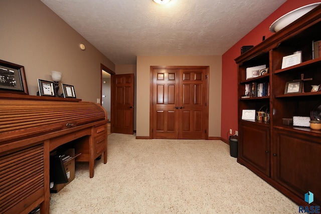 office area with a textured ceiling, light carpet, and baseboards