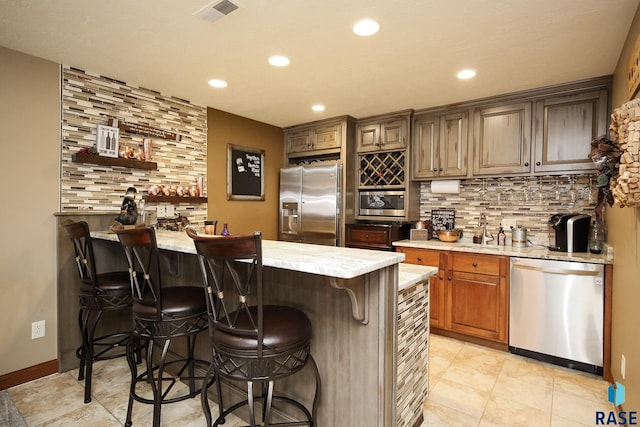 bar with tasteful backsplash, visible vents, appliances with stainless steel finishes, a sink, and recessed lighting