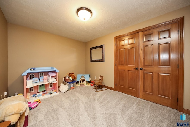 playroom with carpet floors, a textured ceiling, and baseboards