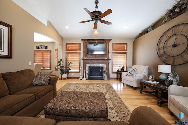 living room featuring a fireplace, a ceiling fan, vaulted ceiling, wood finished floors, and baseboards