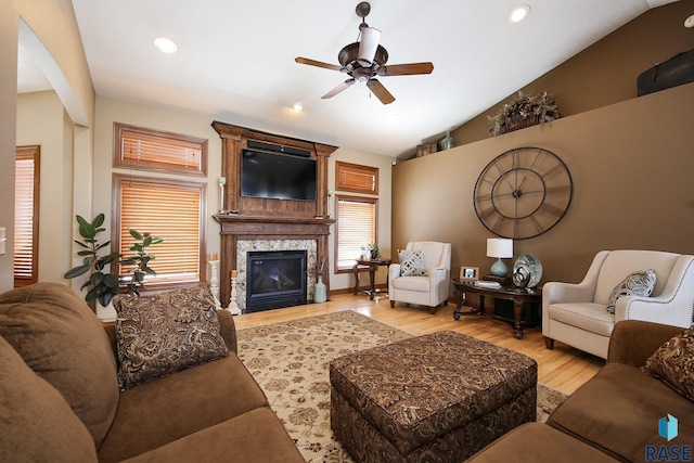 living area with ceiling fan, recessed lighting, a large fireplace, vaulted ceiling, and light wood-type flooring