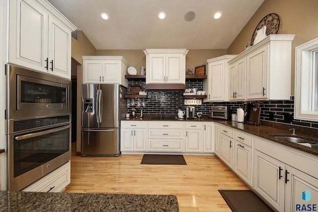 kitchen featuring stainless steel appliances, a sink, light wood-style floors, open shelves, and tasteful backsplash