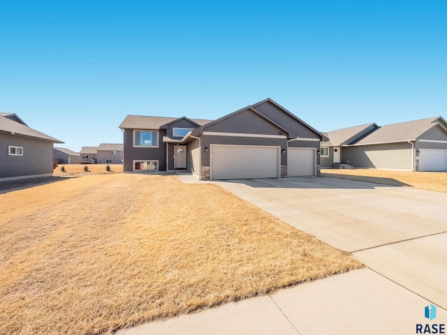 view of front facade featuring a garage, concrete driveway, stone siding, a residential view, and a front yard