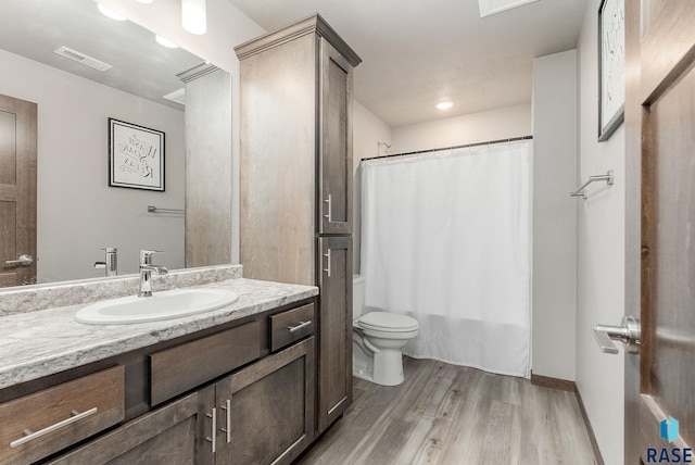 full bathroom with shower / tub combo with curtain, visible vents, toilet, vanity, and wood finished floors