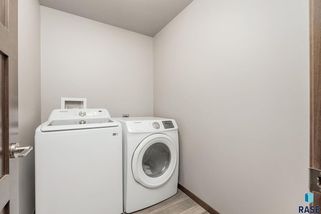 laundry area with laundry area, baseboards, light wood finished floors, and washer and dryer