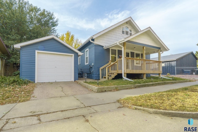 bungalow-style house with a garage, covered porch, concrete driveway, and an outdoor structure