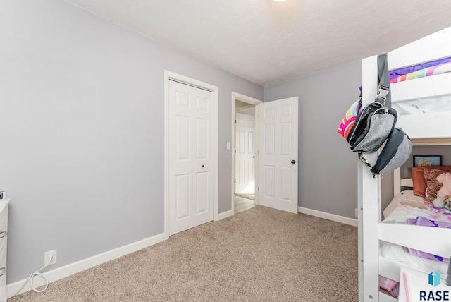 unfurnished bedroom with carpet flooring, a textured ceiling, and baseboards