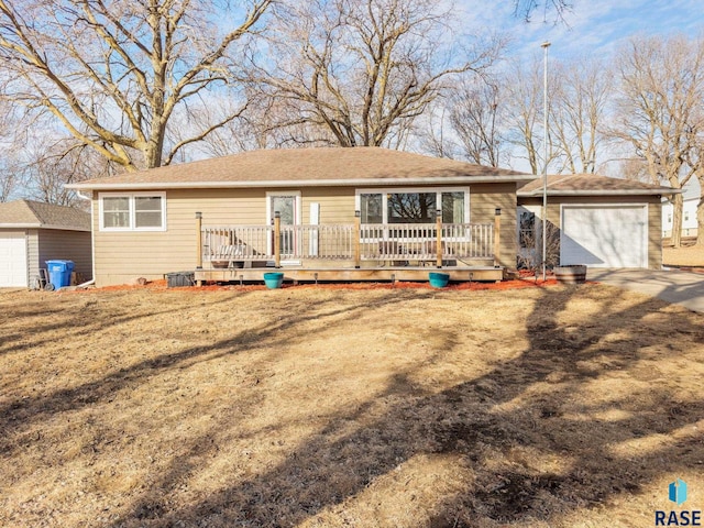 ranch-style house with an attached garage, dirt driveway, a deck, and an outdoor structure