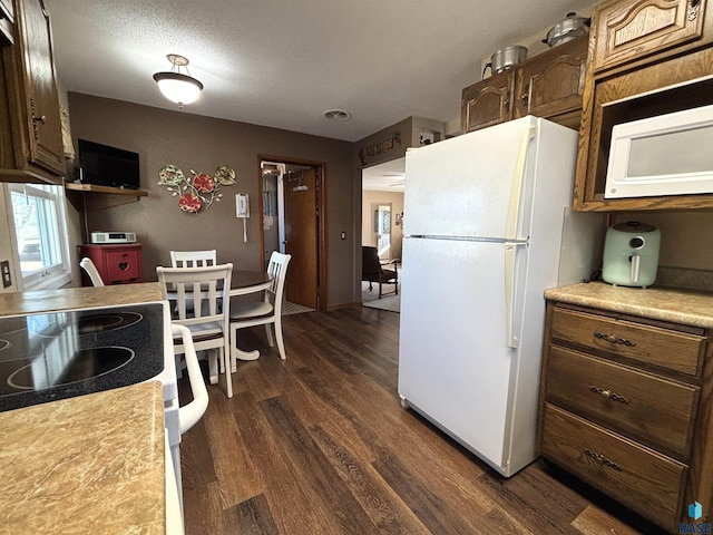 kitchen featuring white appliances, dark wood-style floors, light countertops, and a textured ceiling