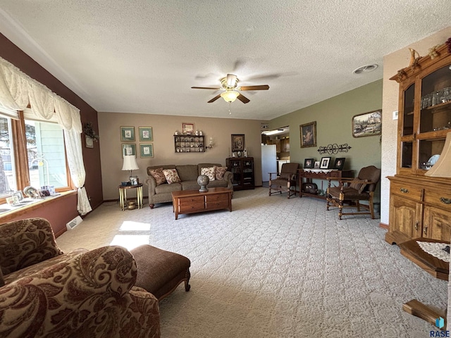 living room featuring a textured ceiling, a ceiling fan, and light colored carpet