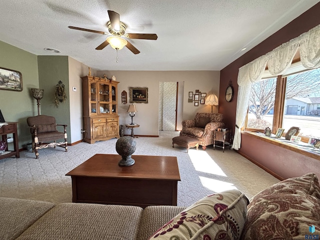 living room featuring carpet, baseboards, ceiling fan, and a textured ceiling