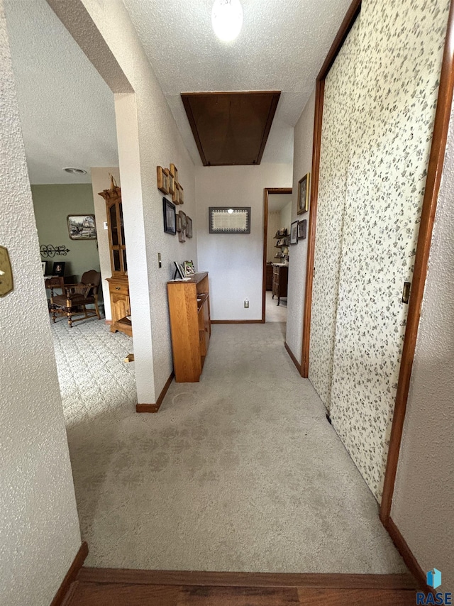 hall with carpet, baseboards, and a textured ceiling