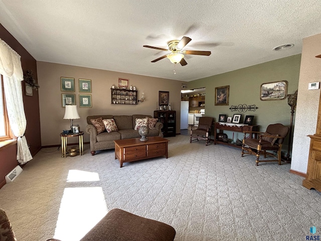 carpeted living area featuring a textured ceiling, ceiling fan, visible vents, and baseboards