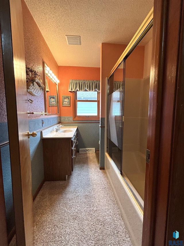 full bathroom with baseboards, visible vents, shower / bath combination with glass door, a textured ceiling, and vanity