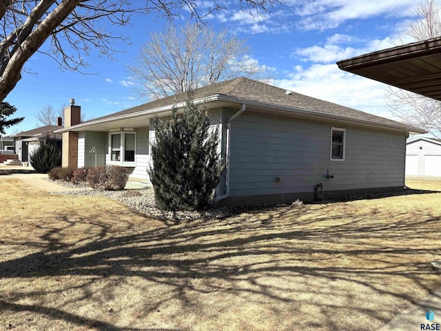 view of home's exterior featuring a garage, roof with shingles, and a chimney