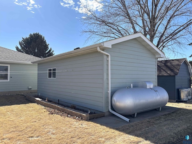 view of side of home with a yard, heating fuel, and central air condition unit