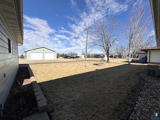 view of yard with an outbuilding, a detached garage, and central air condition unit