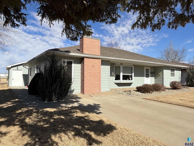 exterior space featuring concrete driveway, brick siding, a chimney, and an attached garage