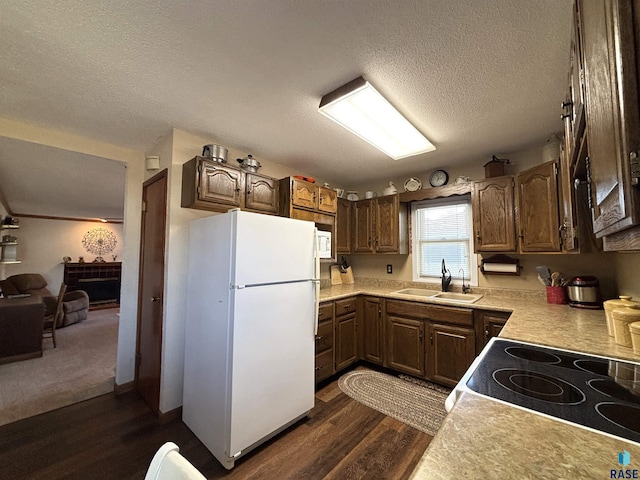 kitchen with a textured ceiling, white appliances, a sink, light countertops, and dark wood-style floors