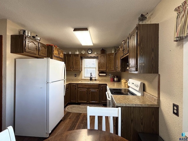 kitchen with a textured ceiling, a textured wall, white appliances, dark wood-type flooring, and a sink