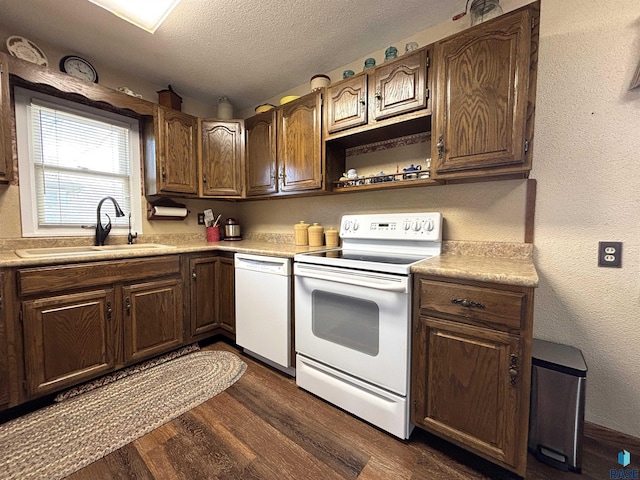 kitchen with white appliances, dark wood-style flooring, light countertops, a textured ceiling, and a sink