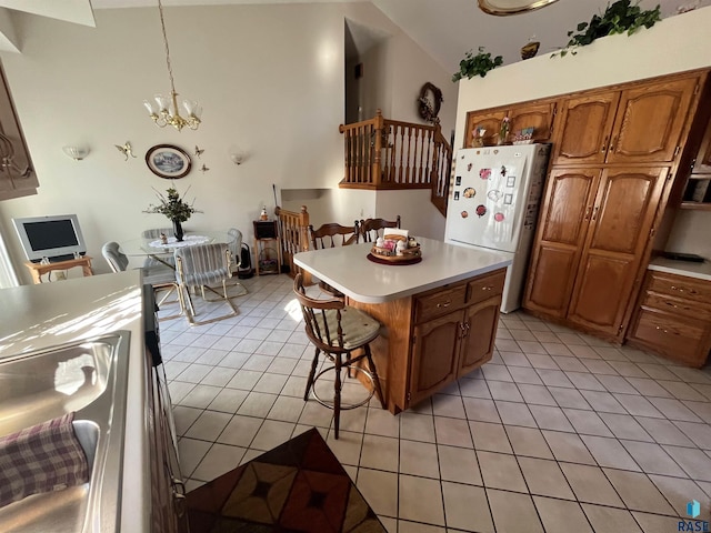 kitchen featuring brown cabinets, freestanding refrigerator, light countertops, and light tile patterned floors