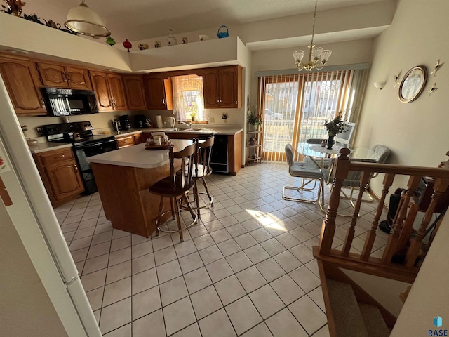 kitchen featuring a chandelier, a breakfast bar, light countertops, black appliances, and pendant lighting