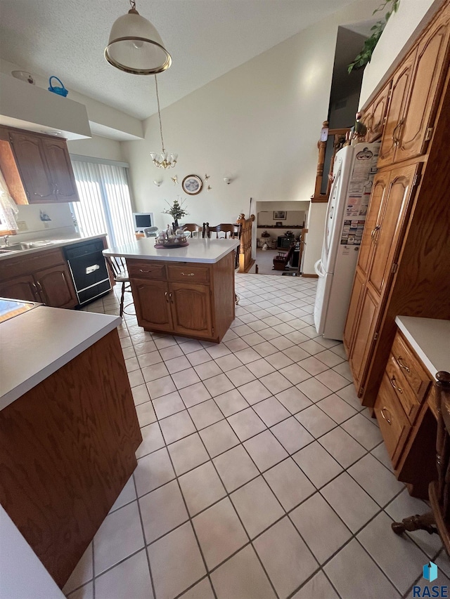 kitchen featuring light tile patterned floors, a kitchen island, freestanding refrigerator, light countertops, and pendant lighting