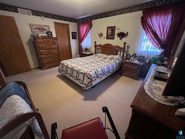 carpeted bedroom featuring a closet, visible vents, and a textured ceiling