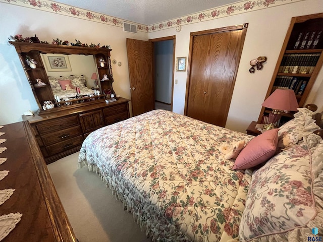 bedroom with carpet, visible vents, and a textured ceiling