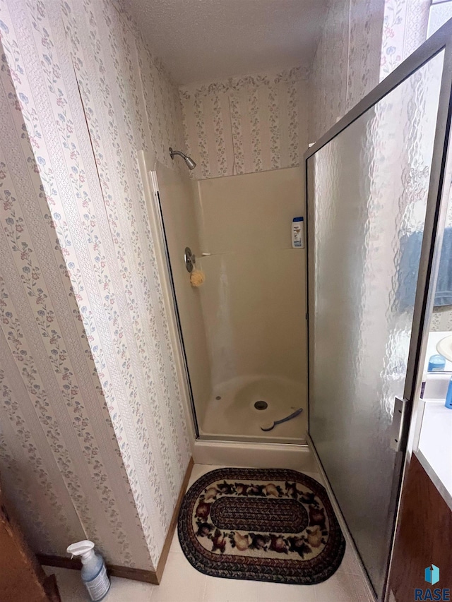 bathroom with baseboards, tile patterned floors, a shower stall, and wallpapered walls