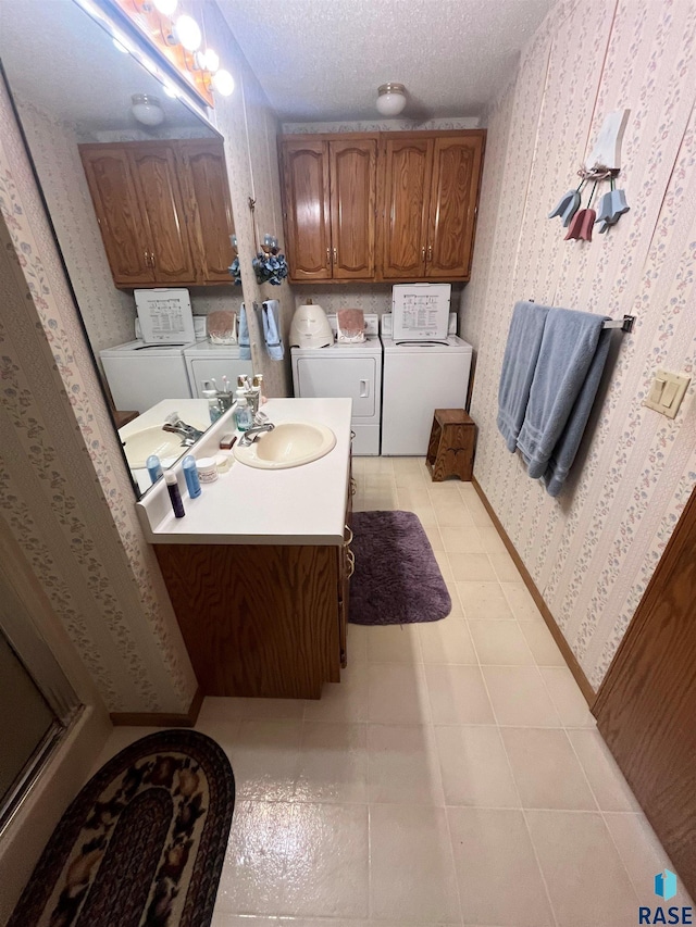 bathroom with a textured ceiling, vanity, baseboards, independent washer and dryer, and wallpapered walls