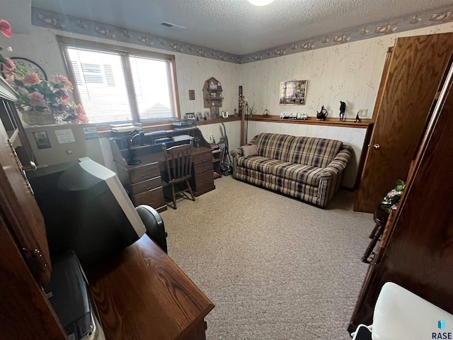 home office with a textured ceiling, carpet, visible vents, and wallpapered walls